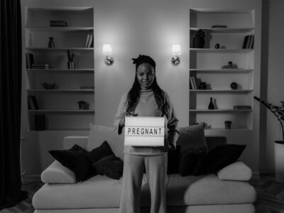 Black pregnant woman holds sign reading