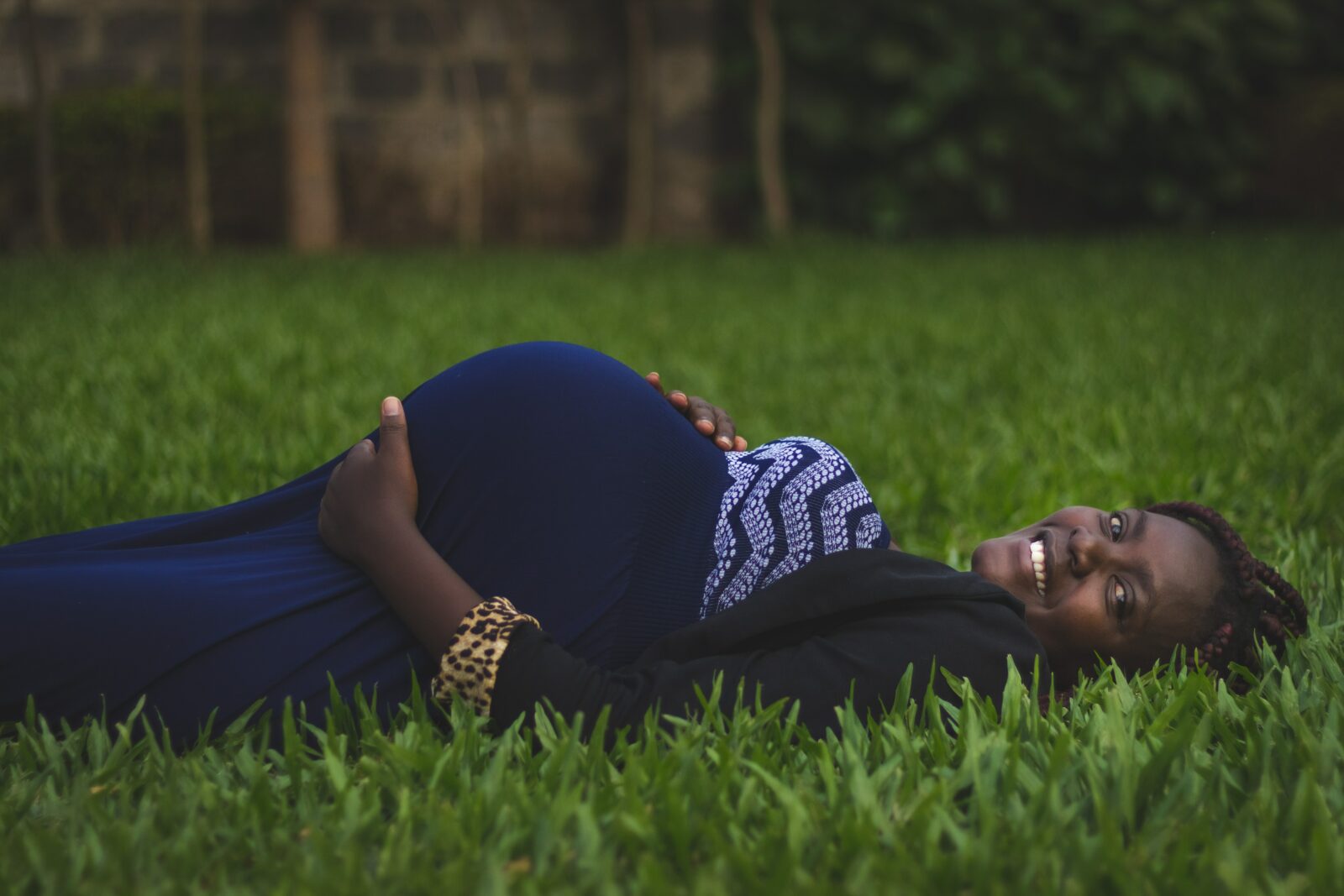pregnant woman lying on green grass on back