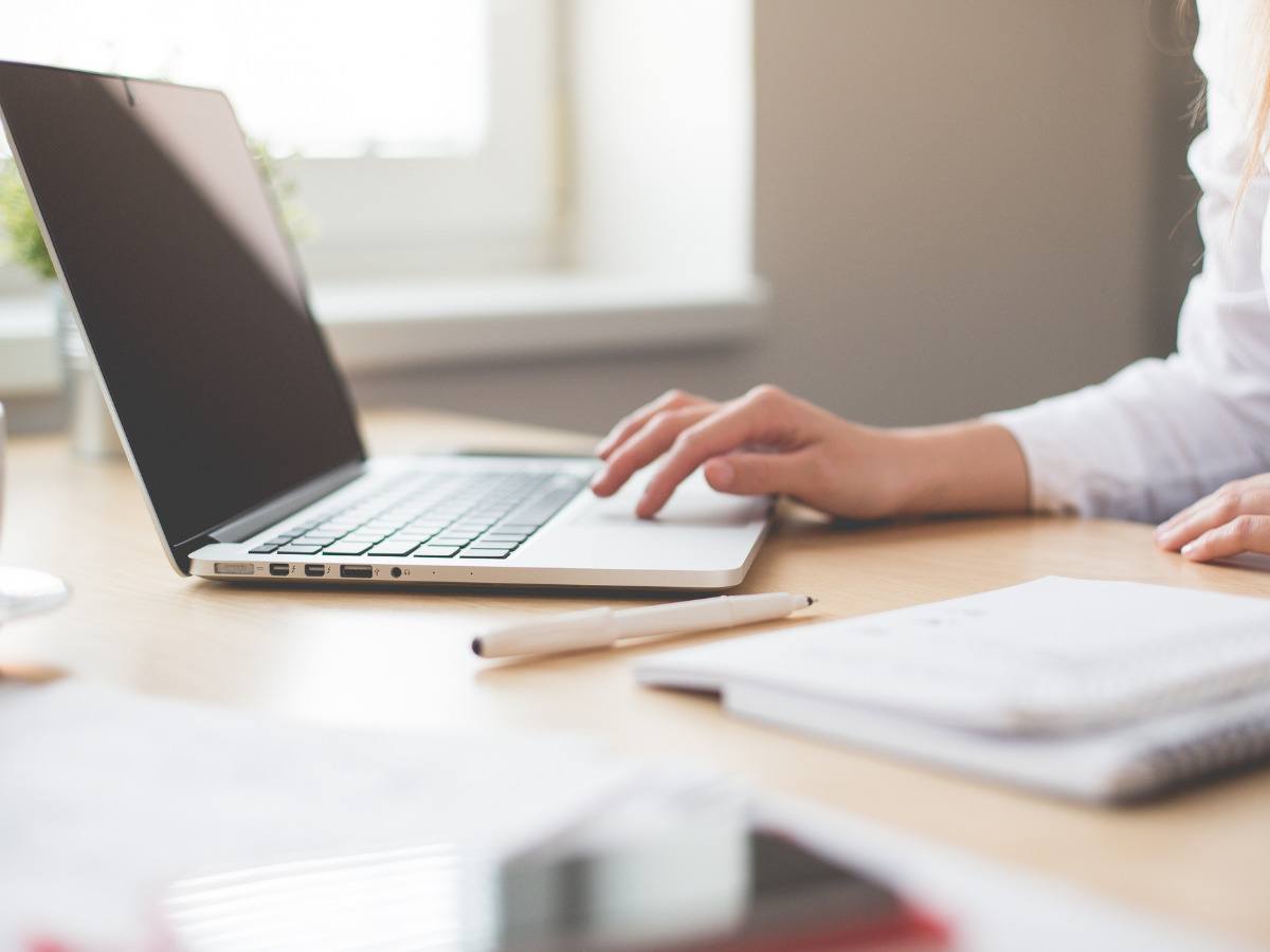 office setting with womans hand resting on a laptop