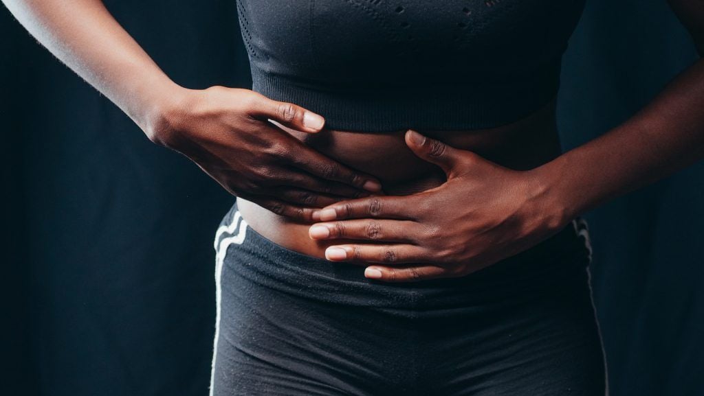 Woman holding her abdomen tentatively as if in pain